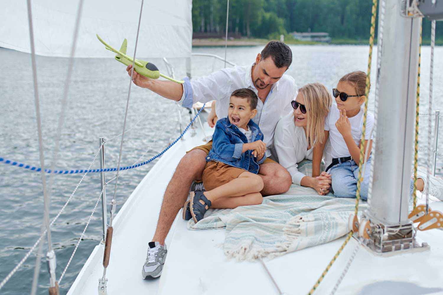 Family On a Boat. Father Playing With Son, Mother and Daughter Wearing Sun Glasses