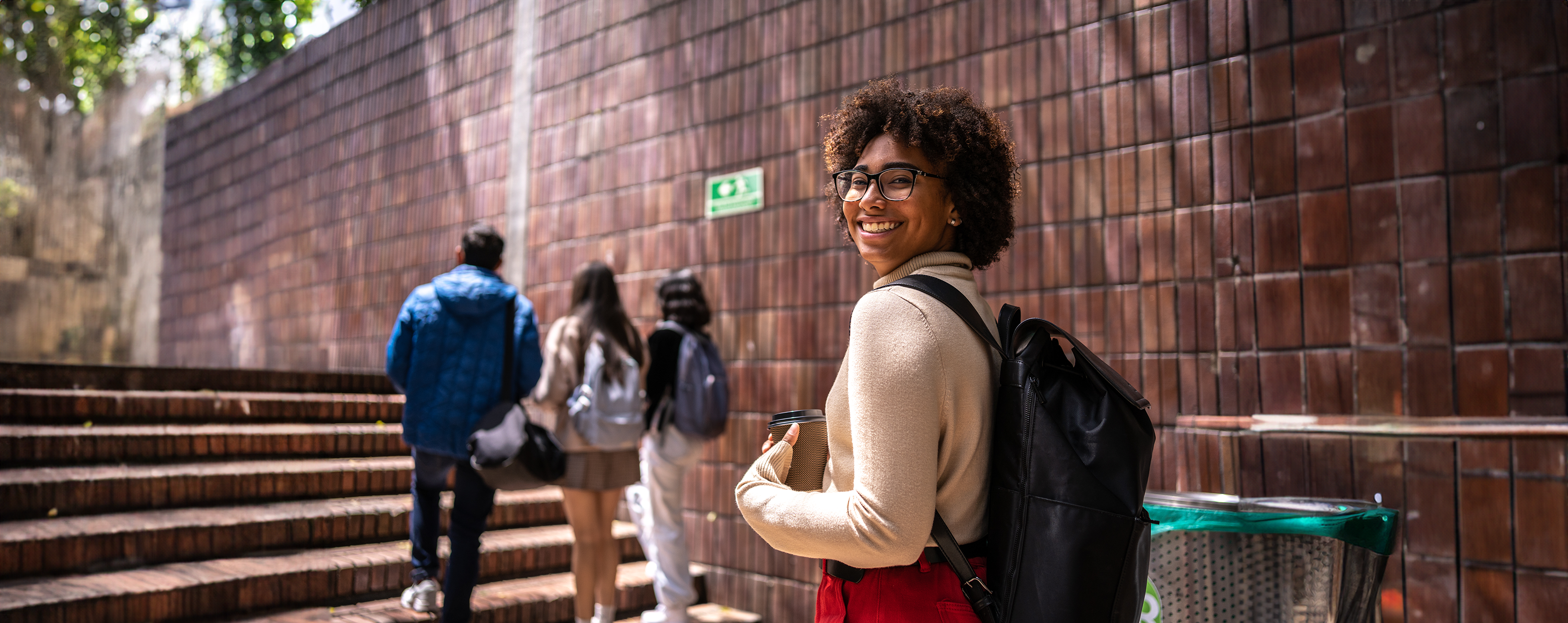 Student wearing a backpack smiles while walking through a campus hallway financial education 