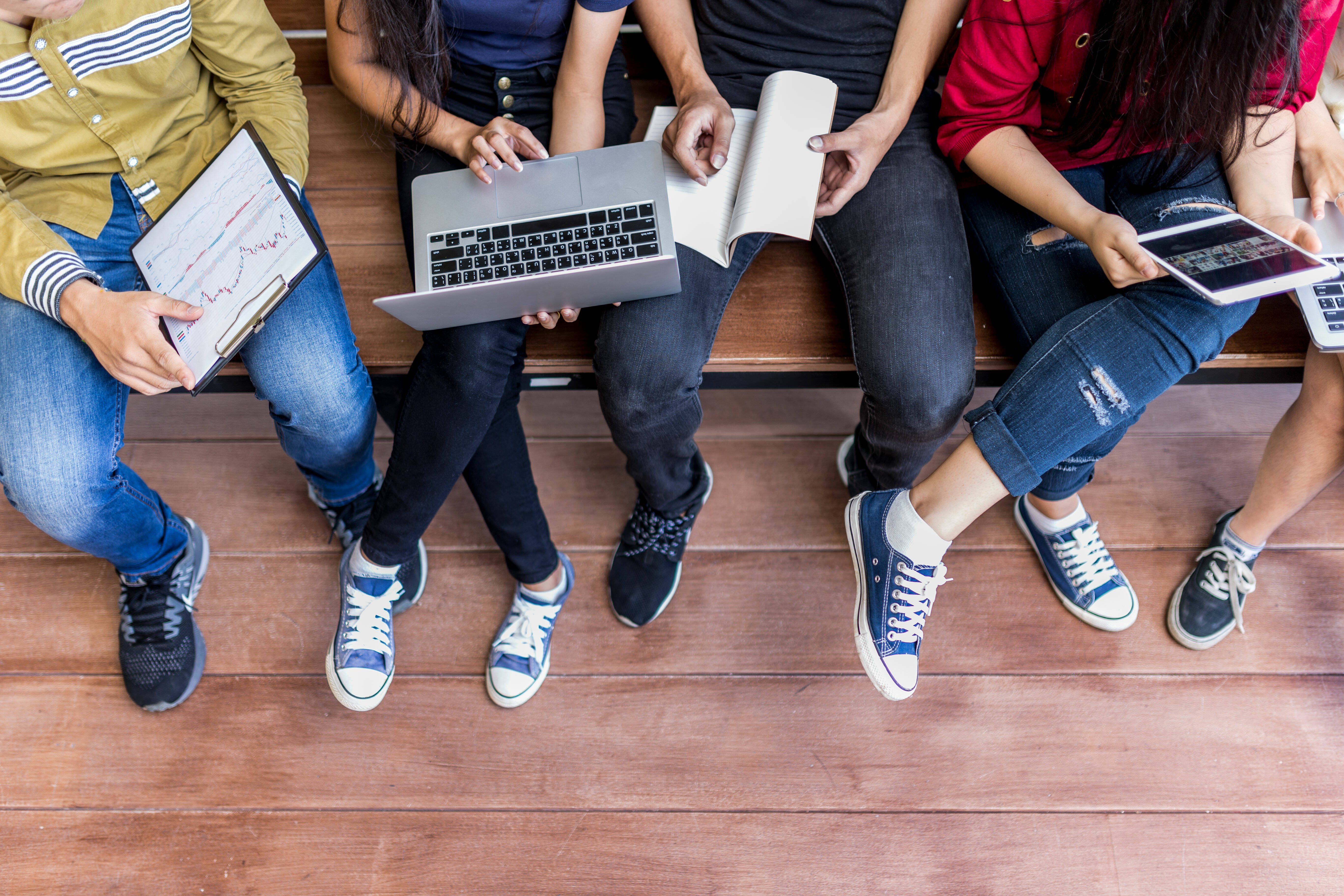 Over shoulder photo of students with notebooks, laptop and tablet