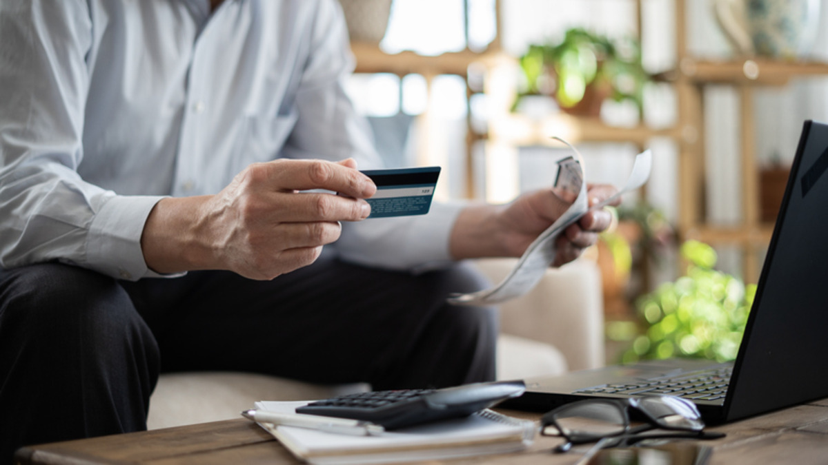 Person holding a credit card while working on a laptop