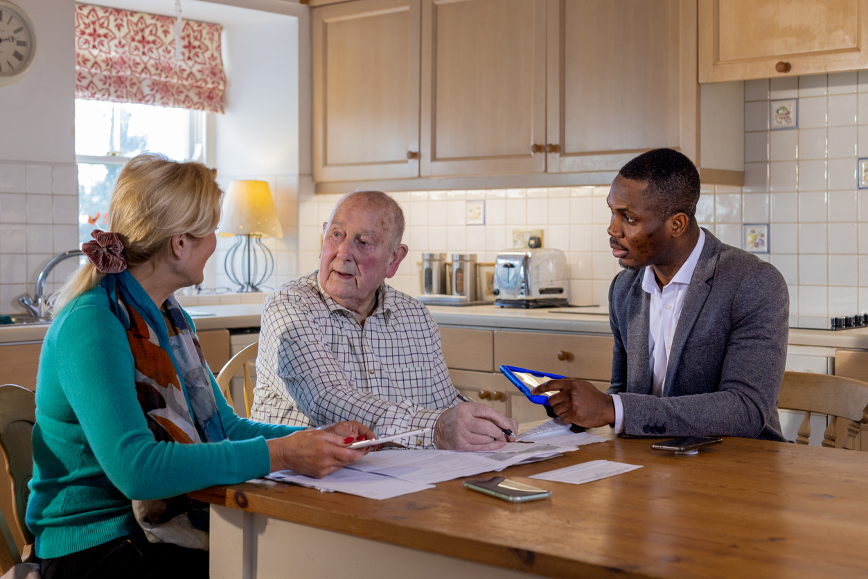 An elderly man and woman sitting at a table with a banker