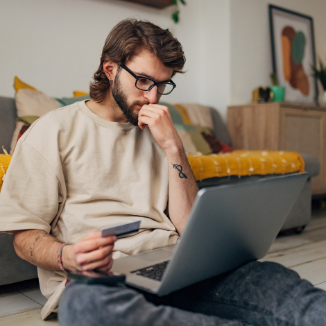 Man holding a credit card while looking at a laptop