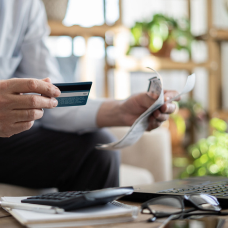 Person holding a credit card while working on a laptop