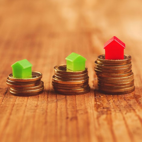 Coins stacked with mini houses on top