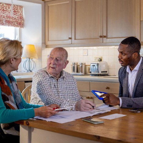 An elderly man and woman sitting at a table with a banker