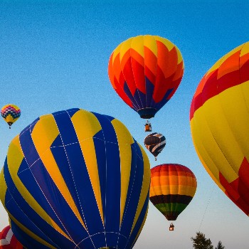 Upward view of several air ballons in the sky at various heights