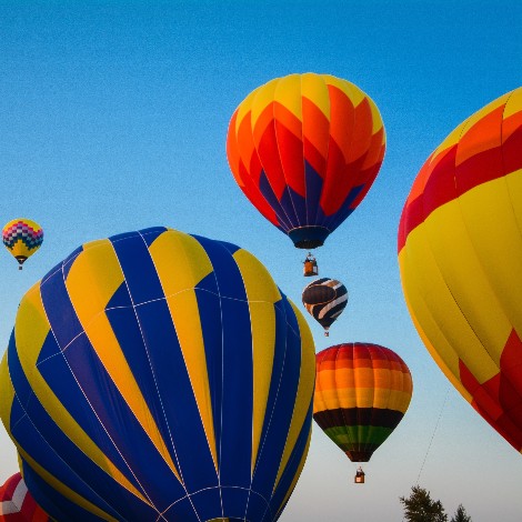 Upward view of several air ballons in the sky at various heights