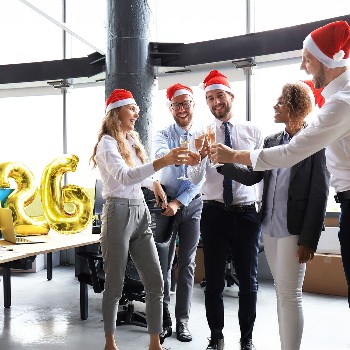 Business people are celebrating holiday in modern office drinking champagne and having fun in coworking. Merry Christmas and Happy New Year 2026