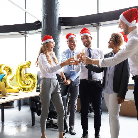 Business people are celebrating holiday in modern office drinking champagne and having fun in coworking. Merry Christmas and Happy New Year 2026