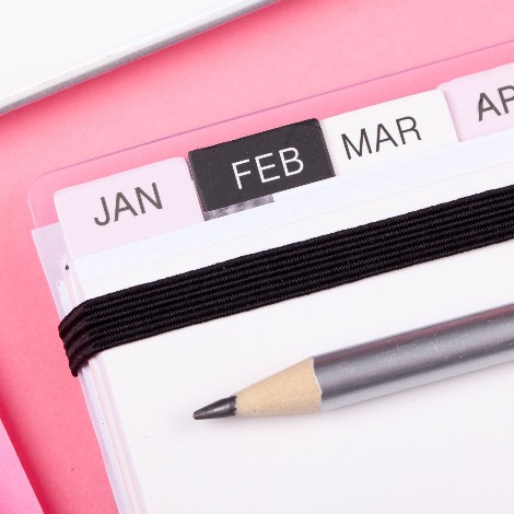 closeup of pink desk with planner showing months from January - April  
