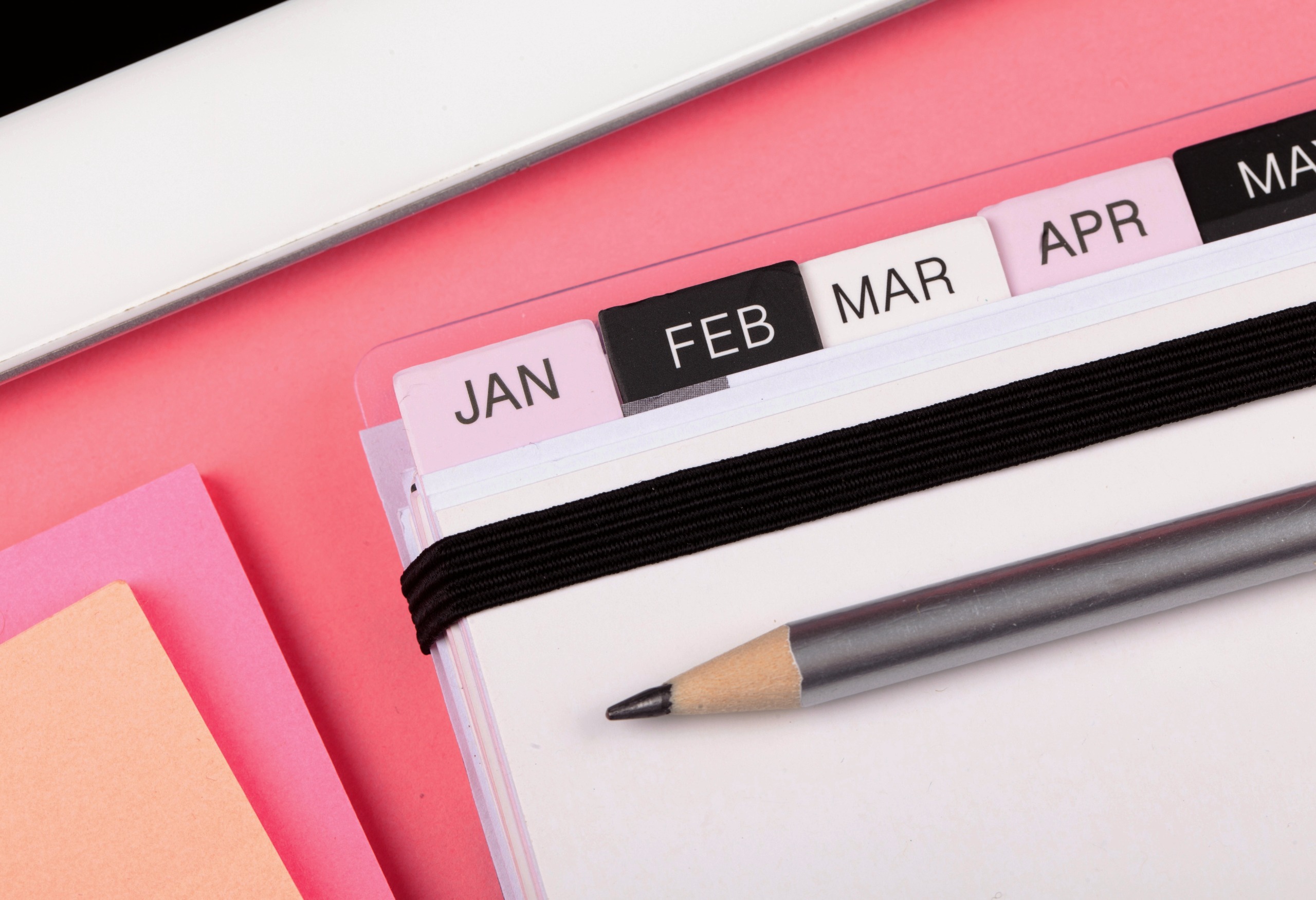 closeup of pink desk with planner showing months from January - April  