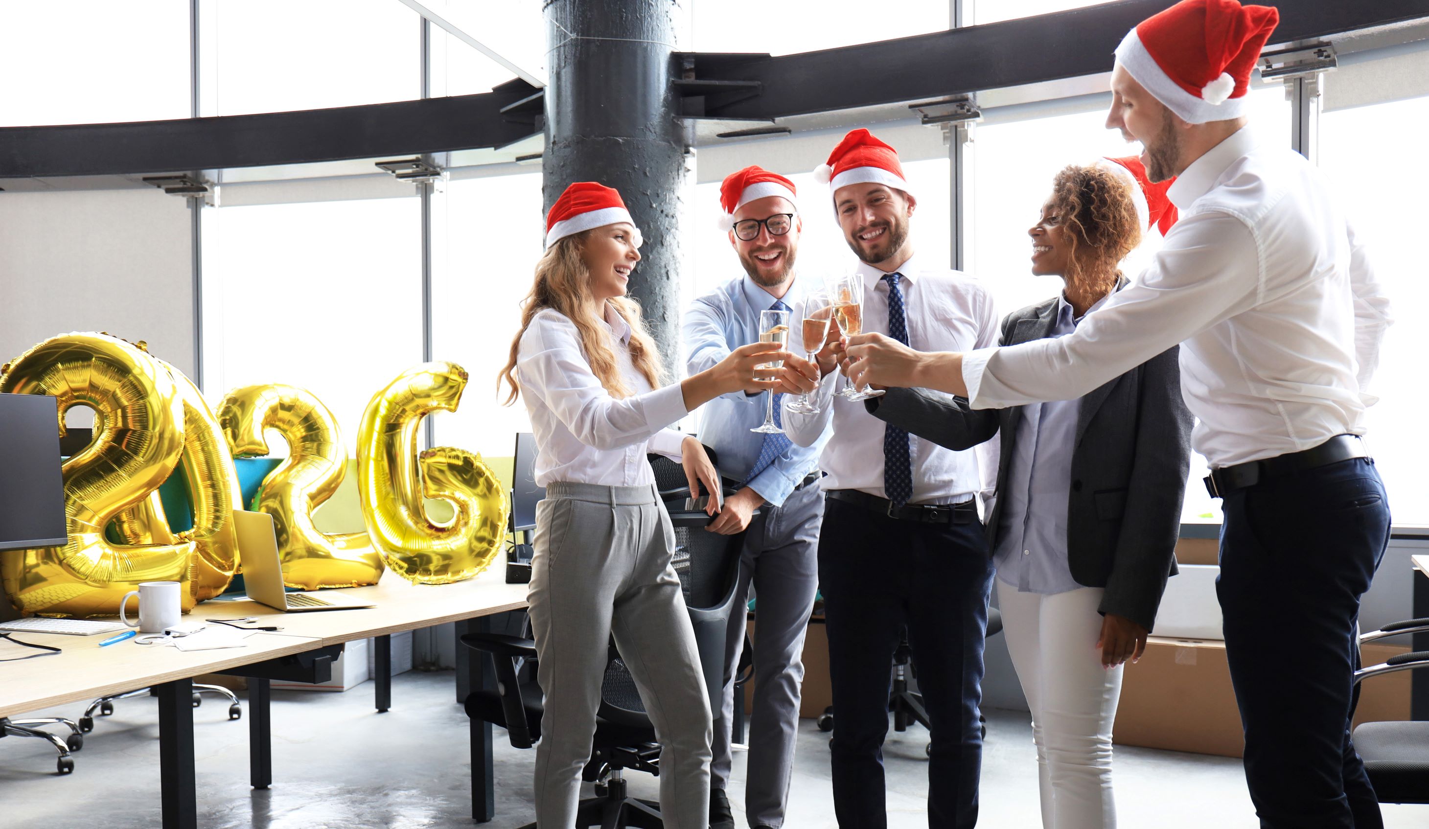 Business people are celebrating holiday in modern office drinking champagne and having fun in coworking. Merry Christmas and Happy New Year 2026