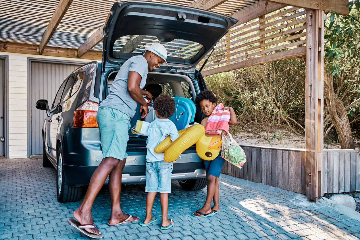 This image shows a family packing a car for summer vacation.